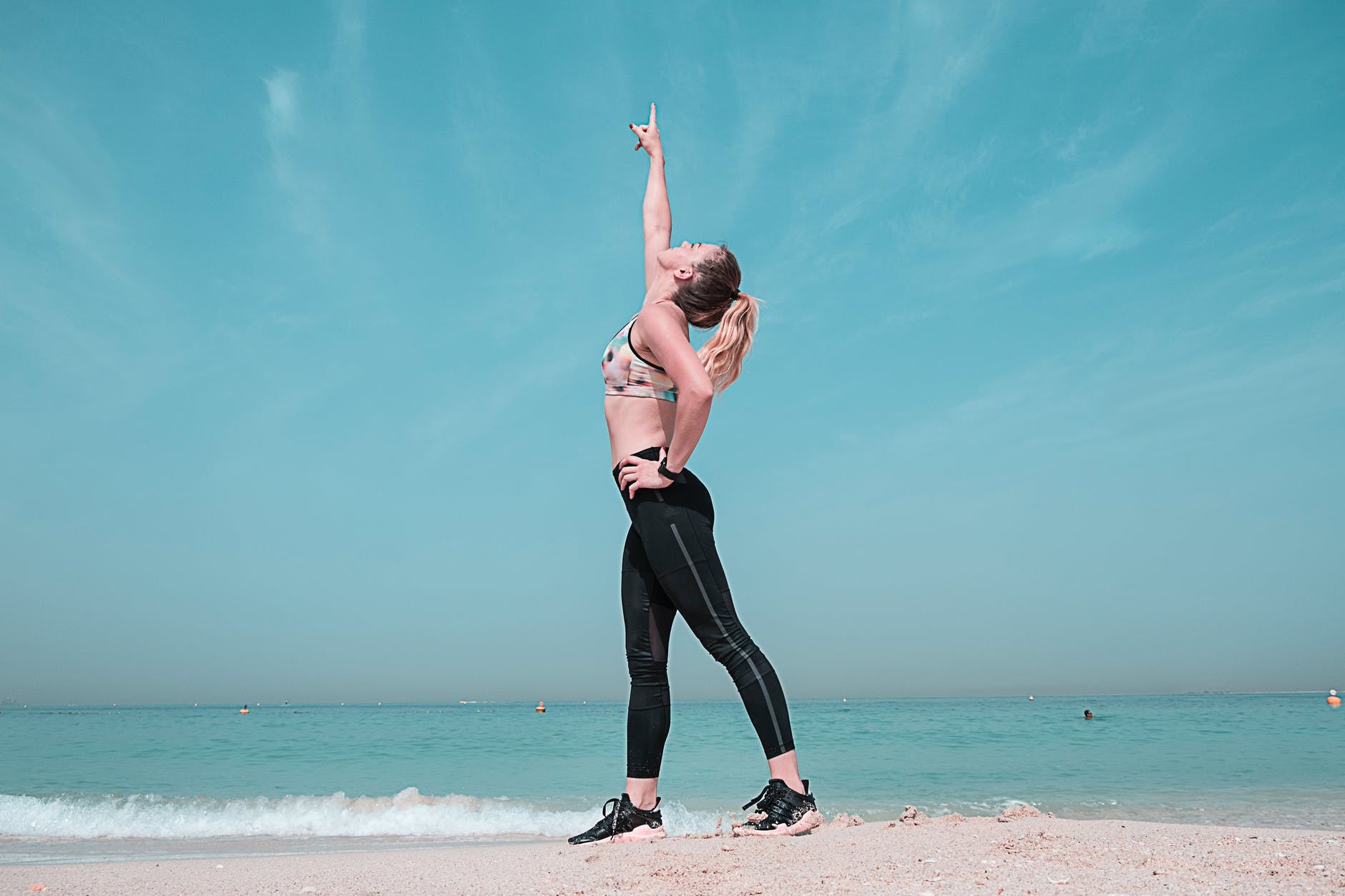 woman pointing at sky on seashore