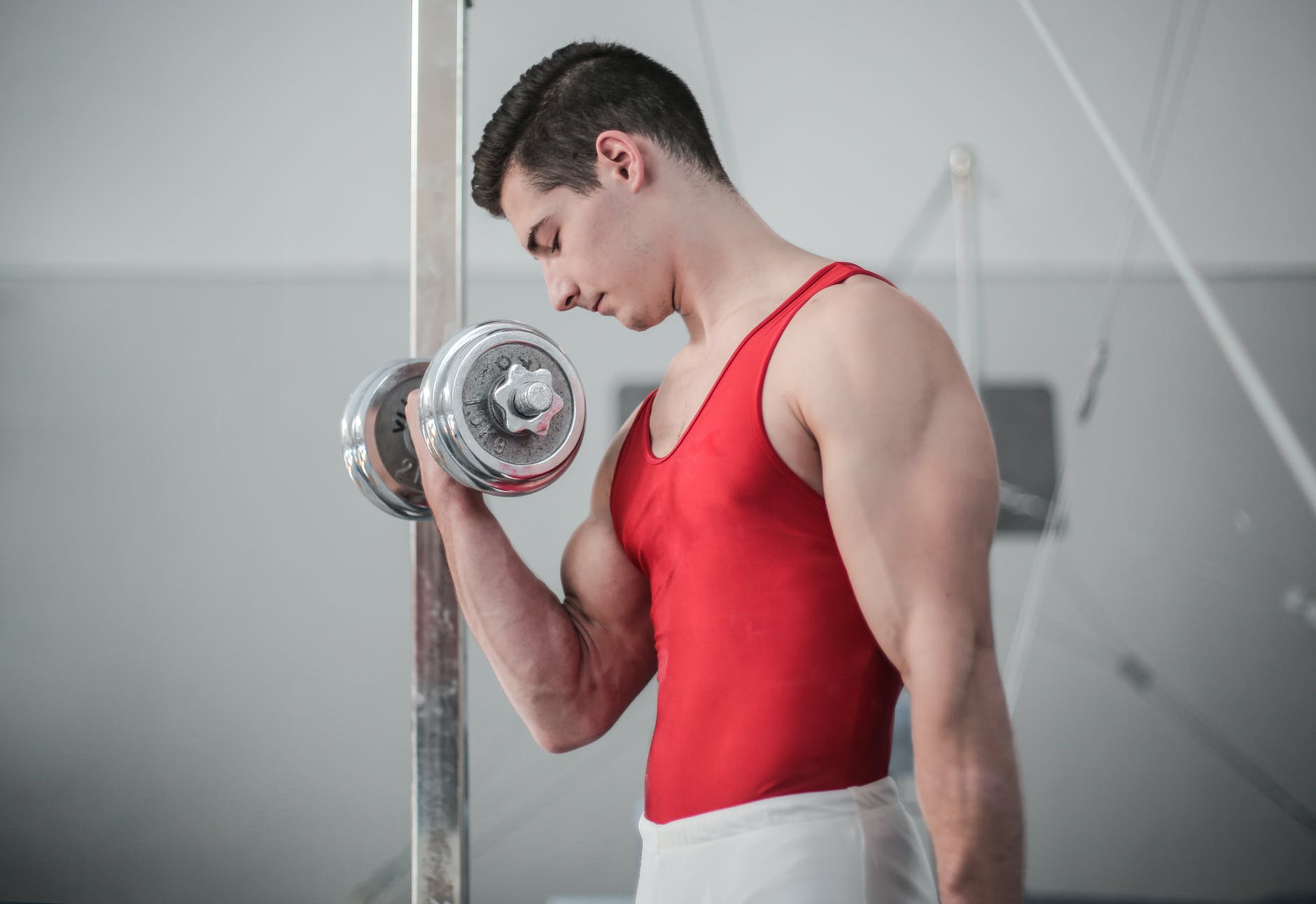 photo of male gymnast doing dumbbell bicep curls