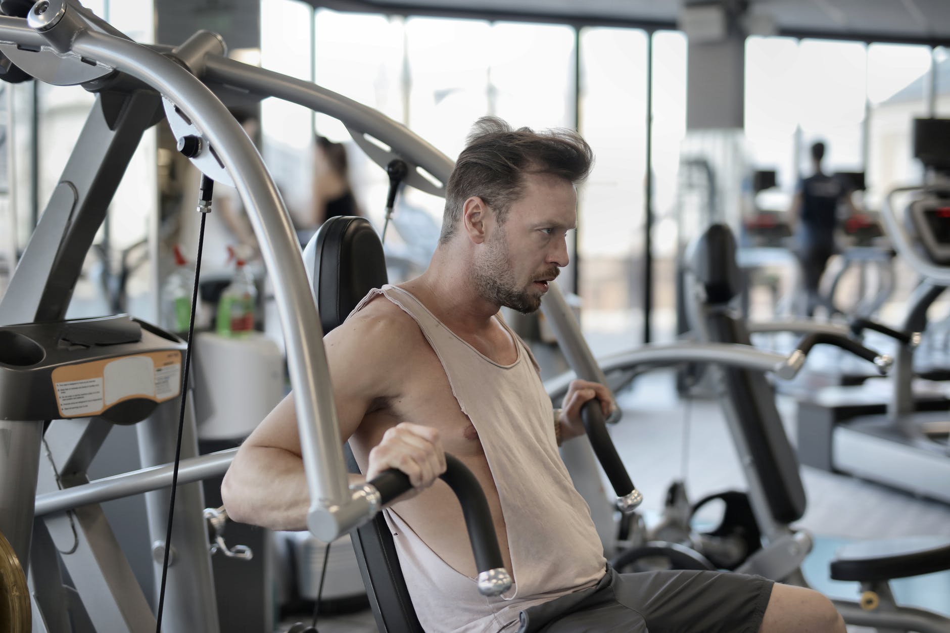 strong sportsman exercising with shoulder press machine in gym