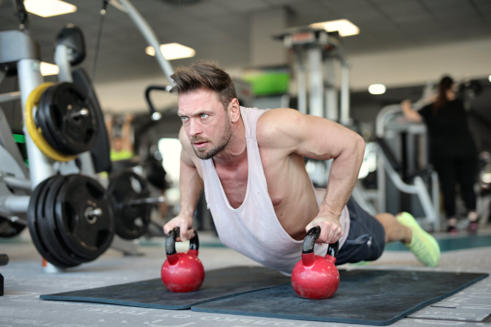 athletic man with fit muscles doing push ups on kettlebells