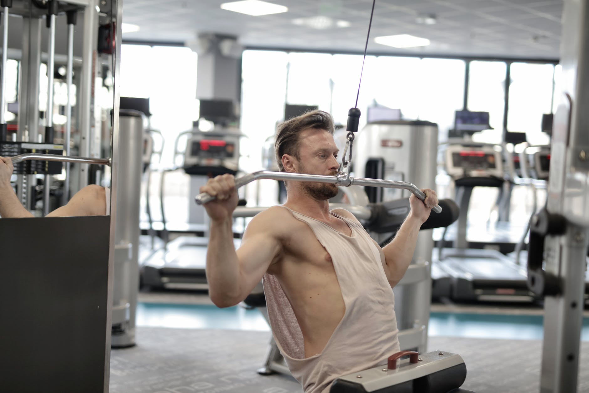 strong serious male athlete practicing on simulator while training in modern gym