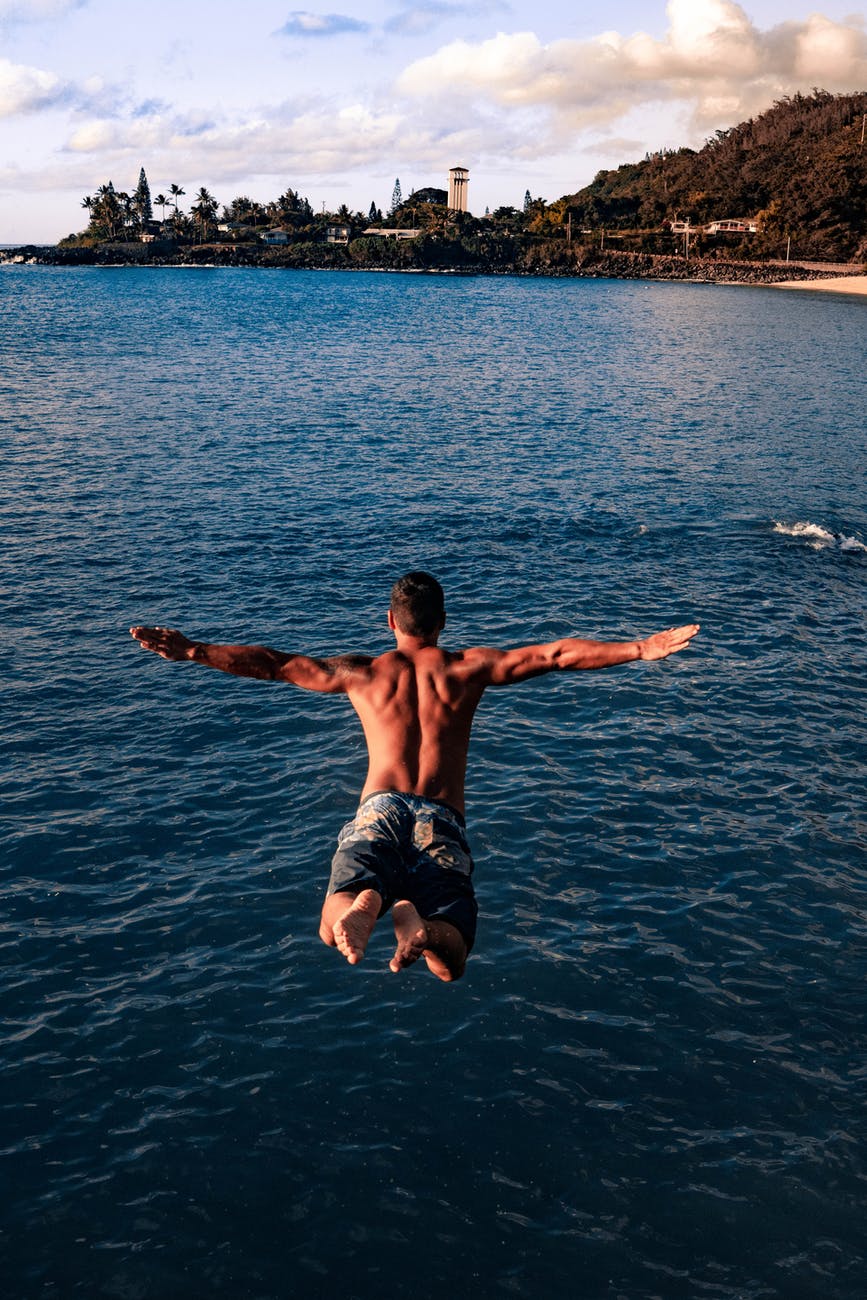 fit young man jumping into ocean