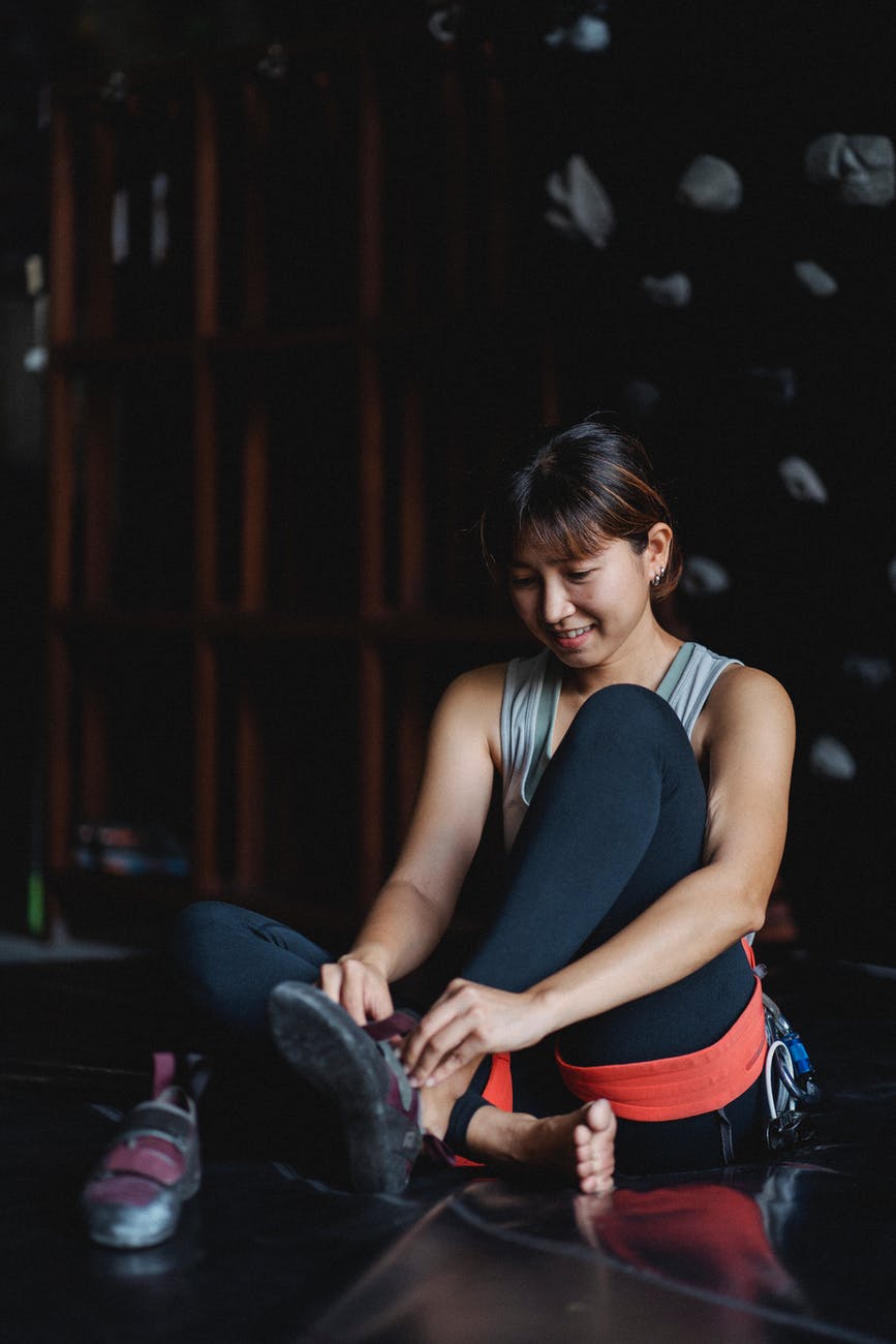 asian sportswoman preparing for training in climbing gym
