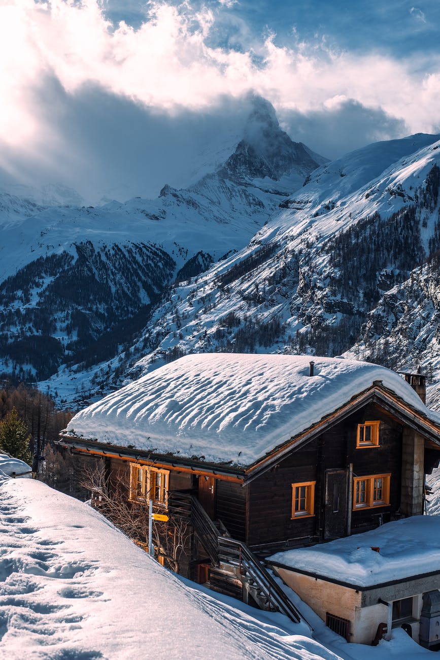 wooden house with snow on roof in winter mountainous terrain