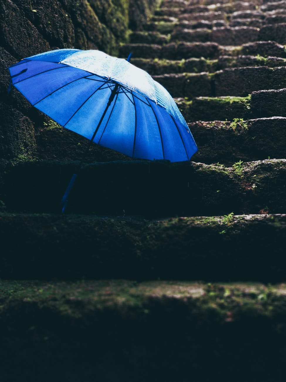 blue umbrella on black stairs