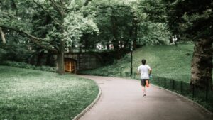 photo of man jogging on paved pathway