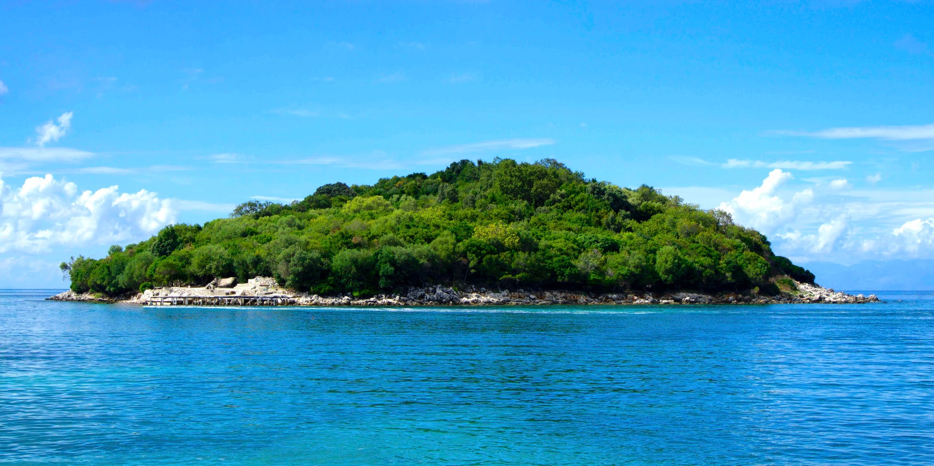 island covered with green trees under the clear skies